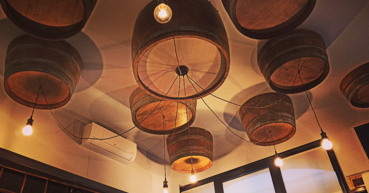 Unique ceiling decor featuring hanging wine barrels (barriques) at Osteria d'Asti restaurant in Arona, Italy