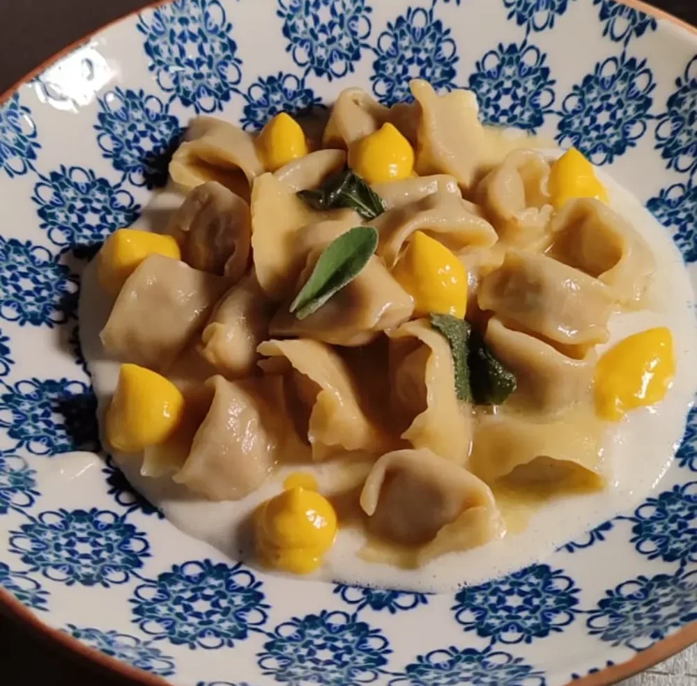 Raviolini del Plin fatti a mano ripieni di ossobuco con salsa allo zafferano, un incontro tra la tradizione piemontese e milanese all'Osteria d'Asti.